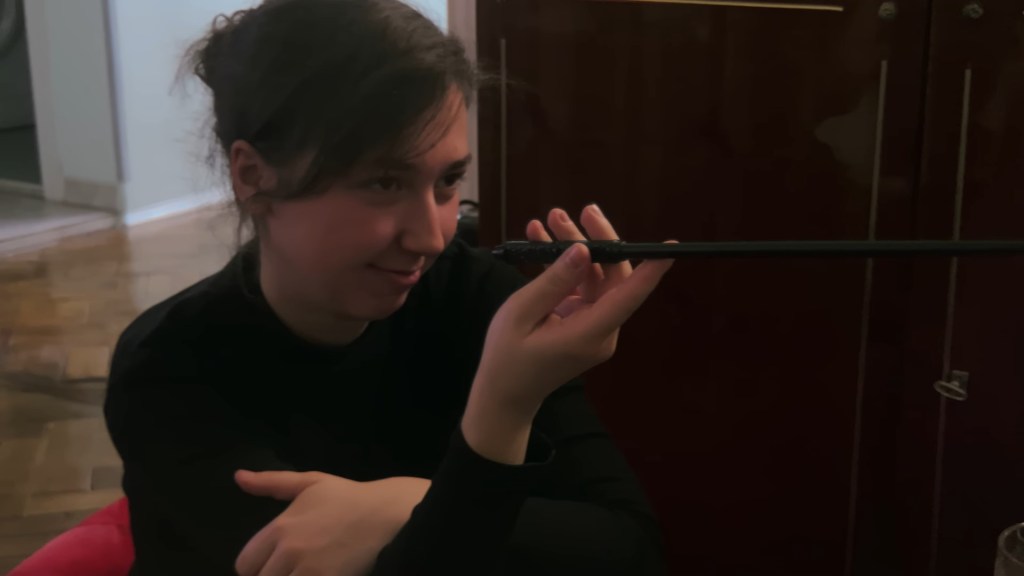Medium shot of Ksenia's friend inspecting a replica of Severus Snape's wand