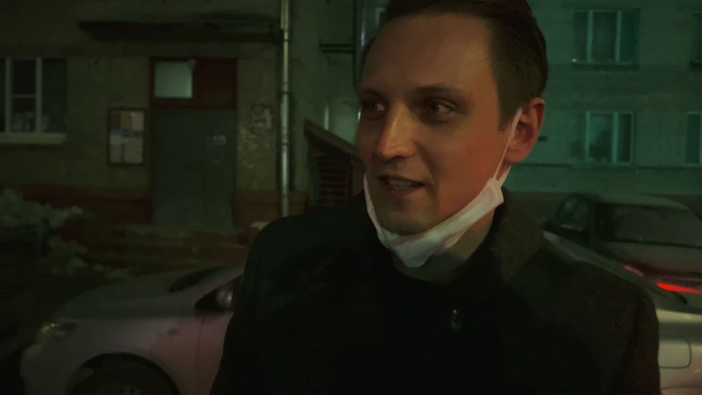 Close-up of Dima talking outside at night with a mask around his chin