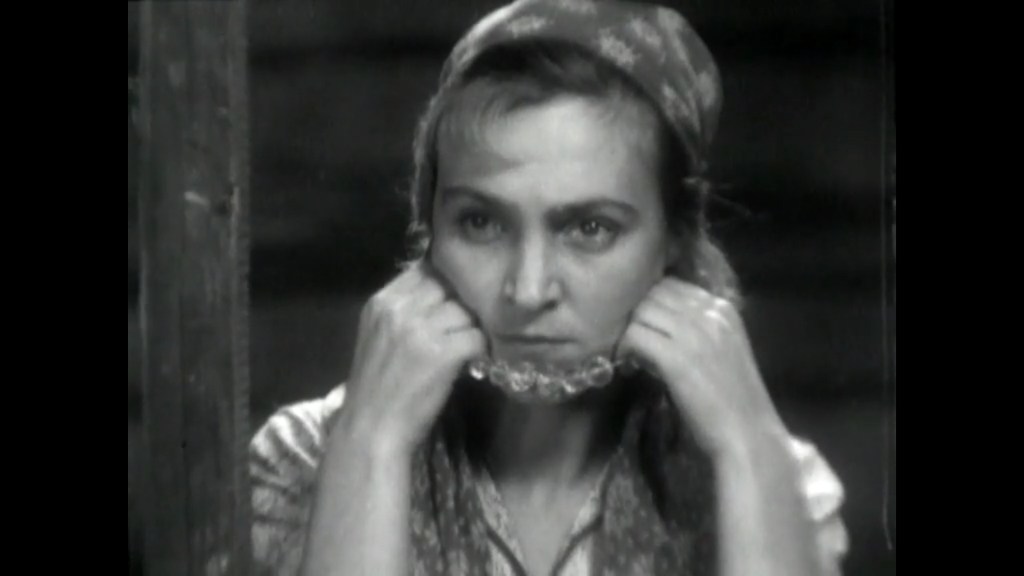 Close-up of Yelena Kuzmina's Maria holding the pearl necklace Nikolay Kryuchkov's Alyosha gave her up in front of her face