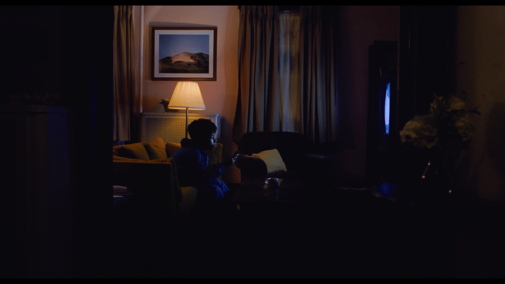 Medium long shot of young Owen watching TV in his living room