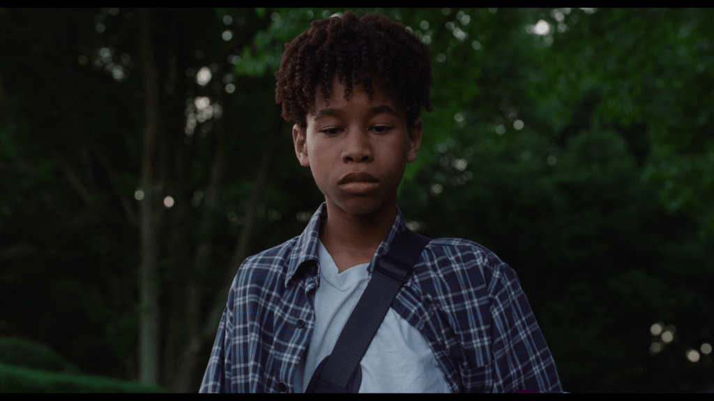 Close-up of Owen walking toward the camera through the woods