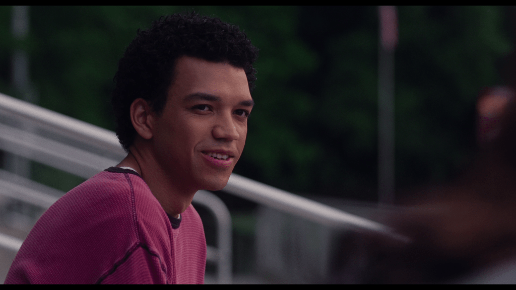 Close-up of Owen smiling nervously from the left side of the frame as he looks offscreen to the right where Maddy sits