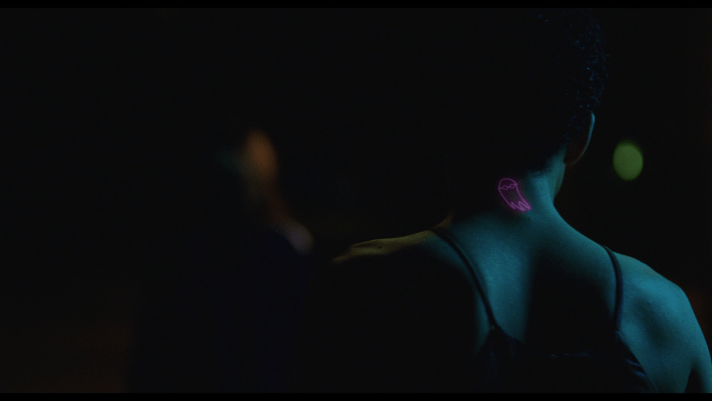 Medium shot of Owen's back, where the ghost tattoo Maddy gave him glows pink