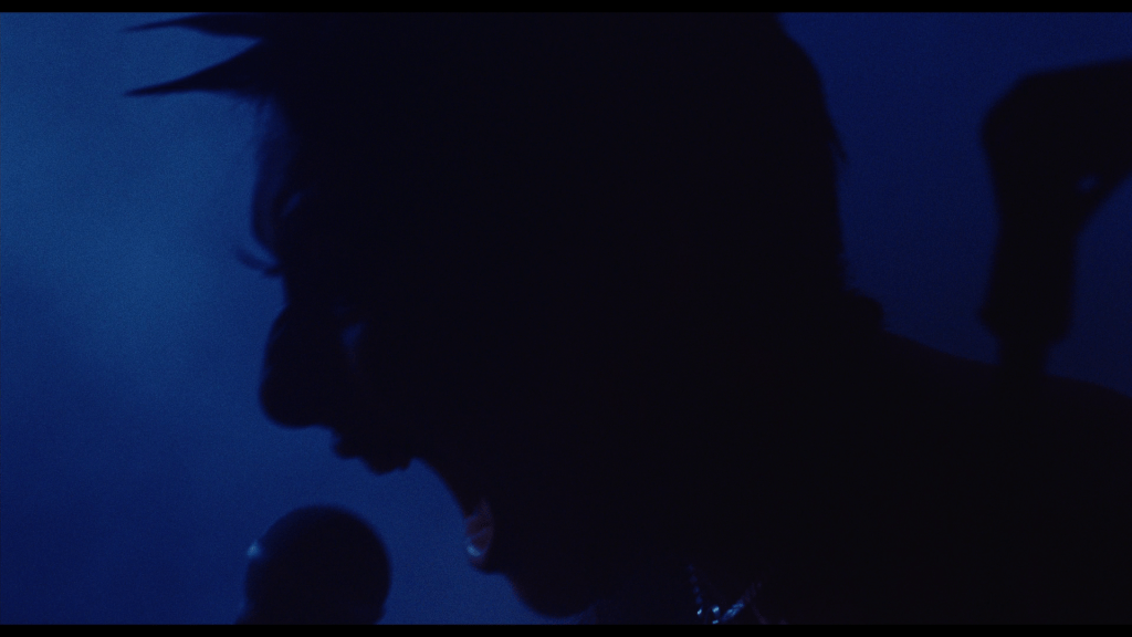 Close-up of King Woman screaming in silhouette against a blue backdrop