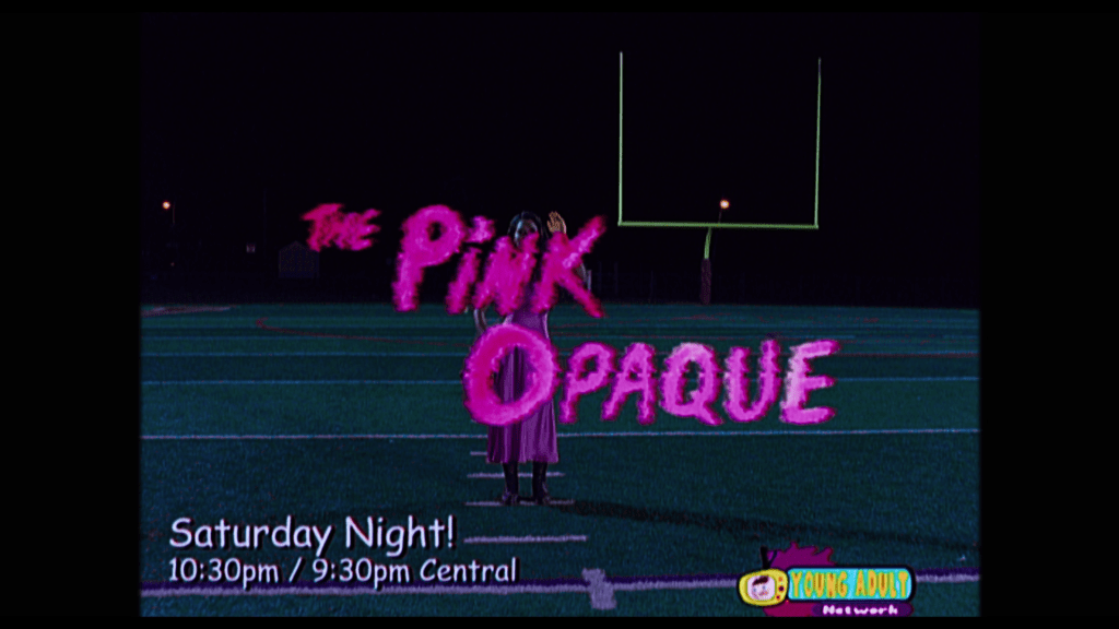 Continuation of the shot: Isabel appears to be waving at the viewer, but is obscured by the words "The Pink Opaque" in a neon pink font