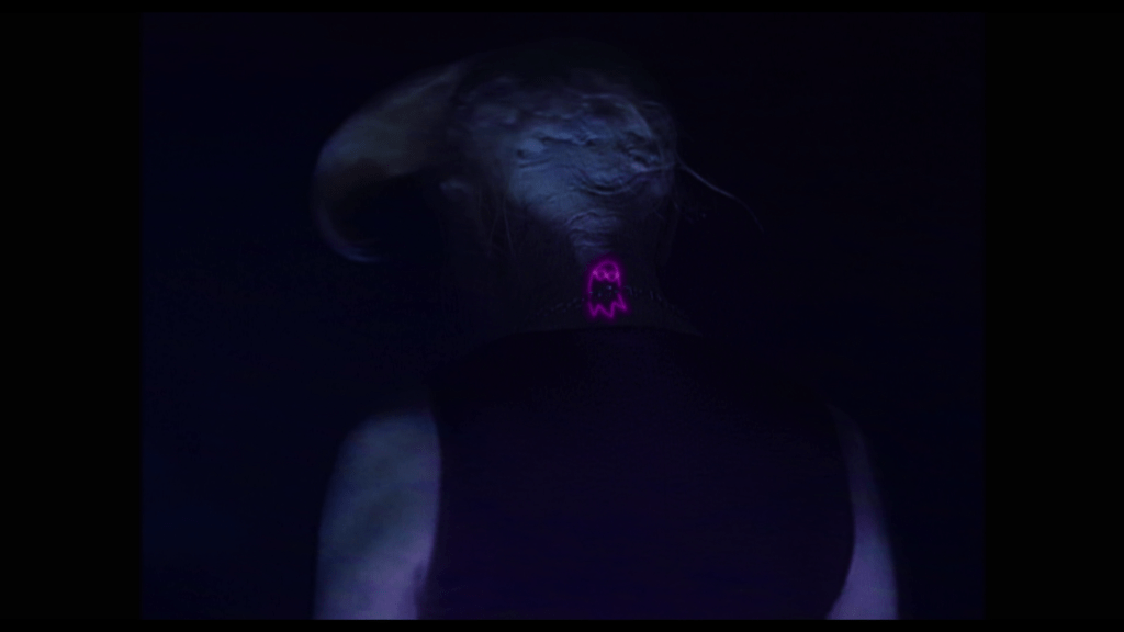 Medium close-up of the ghost birthmark that Isabel though belonged to Tara glowing pink on what we now realize is the back of Marco's neck