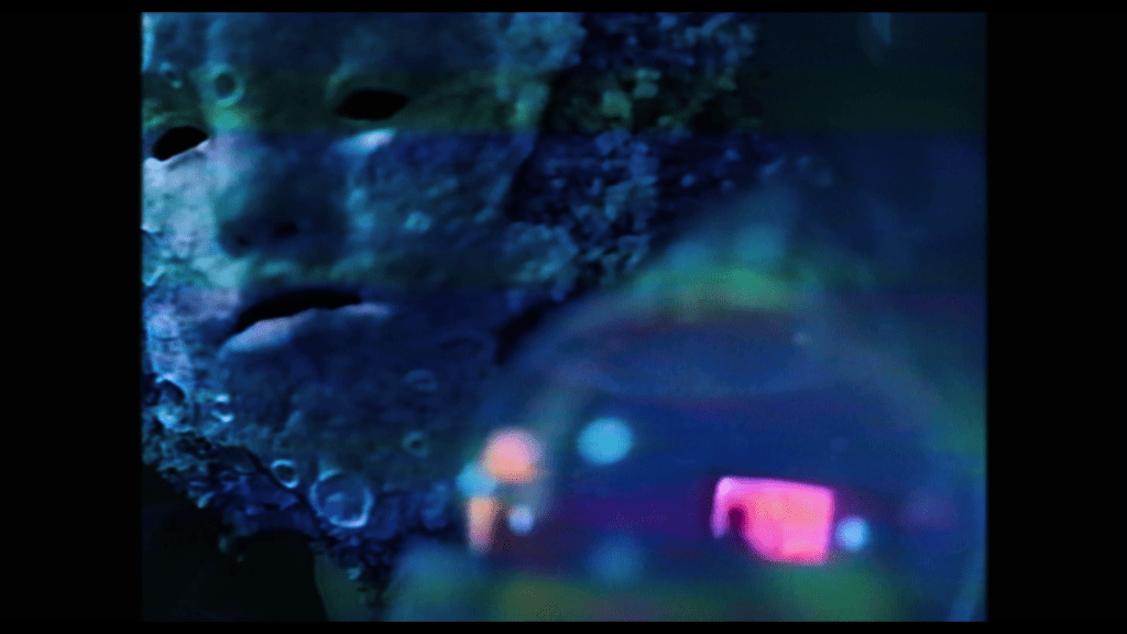 Close-up of Mr. Melancholy holding a snow globe up to Isabel's face which contains the scene of young Owen watching TV in his living room that I Saw the TV Glow began with