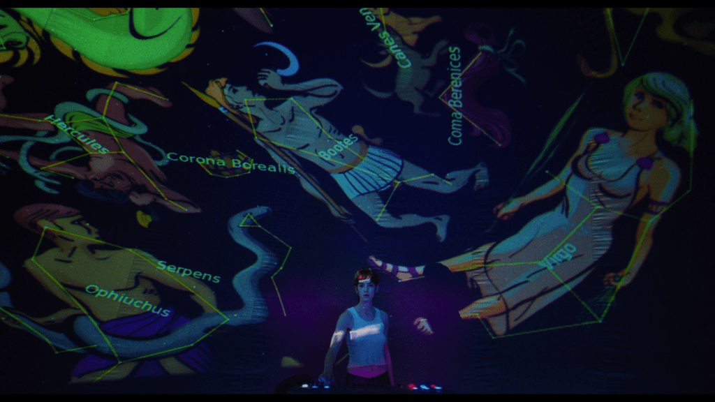 Long shot of Maddie turning a switch which causes illustrations of the constellations to appear above and behind her