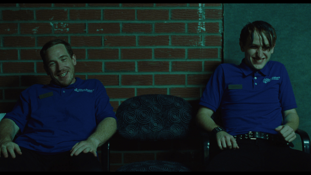 Medium shot of Dave and another one of Owen's movie theater colleagues laughing at him
