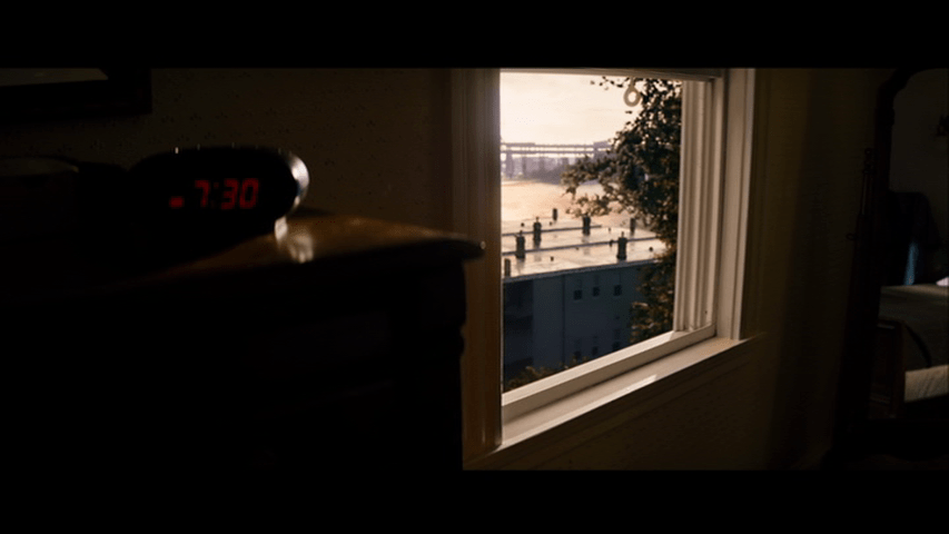Close-up of an alarm clock atop a dresser in front of a window