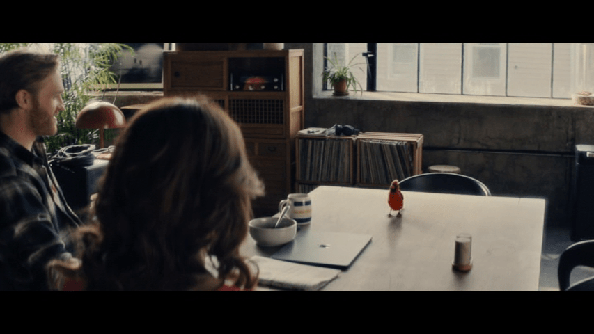 Medium long shot of a cardinal on a dining room table over the shoulder of Emily Blunt's Margaret Fairchild