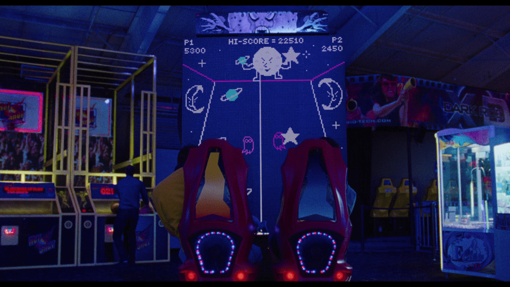 Medium close-up of a two-player shoot'em up arcade game featuring graphics that look like Mr. Melancholy, Marco and Polo, and the ghost birthmarks from The Pink Opaque, but which isn't labeled as being affiliated with a TV show by that name