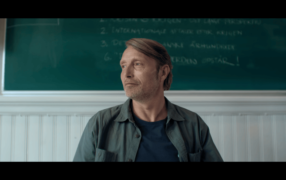 Medium close-up of Martin looking depressed in front of the blackboard in his classroom