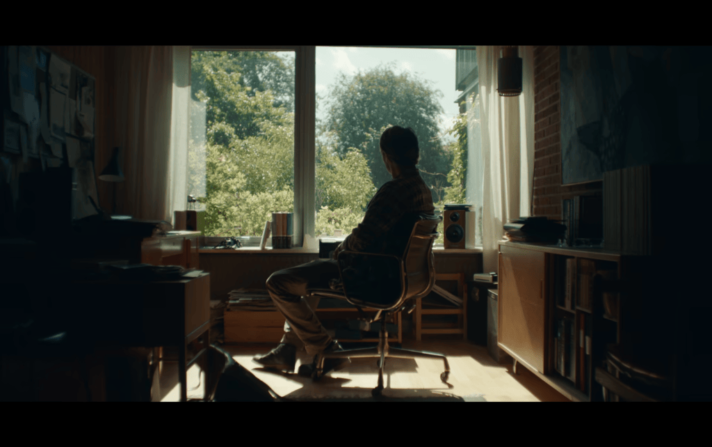 Long shot of Martin sitting in a chair in a home office silhouetted by a window