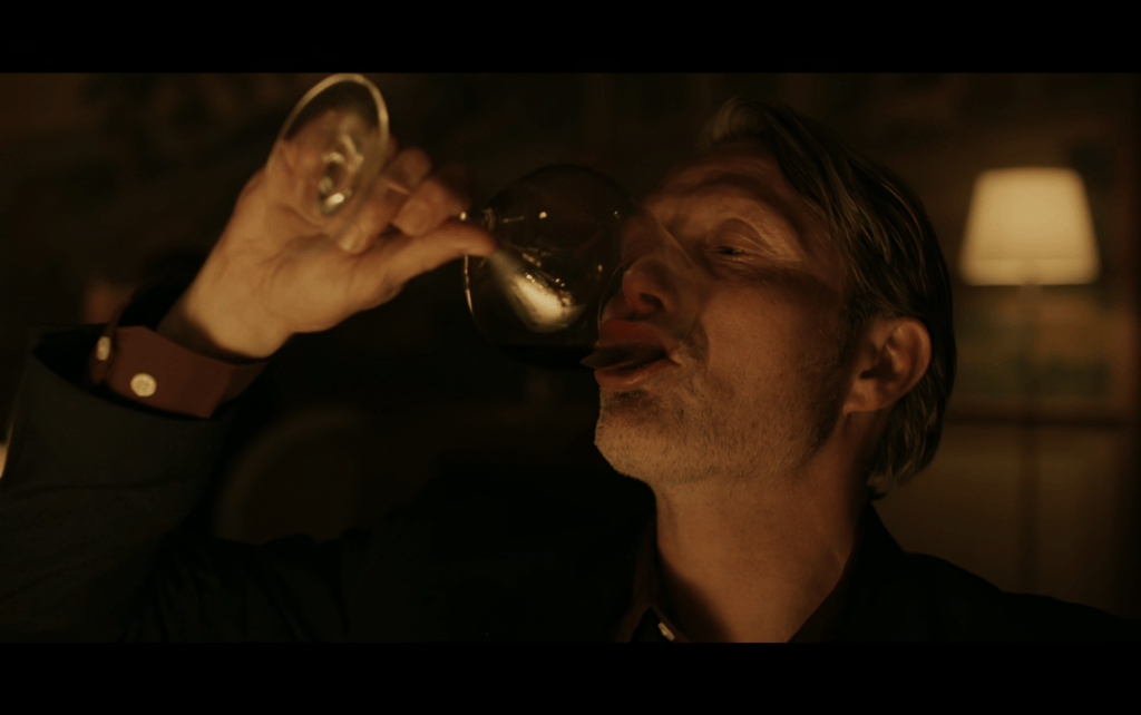 Close-up of Martin downing a glass of red wine in one gulp