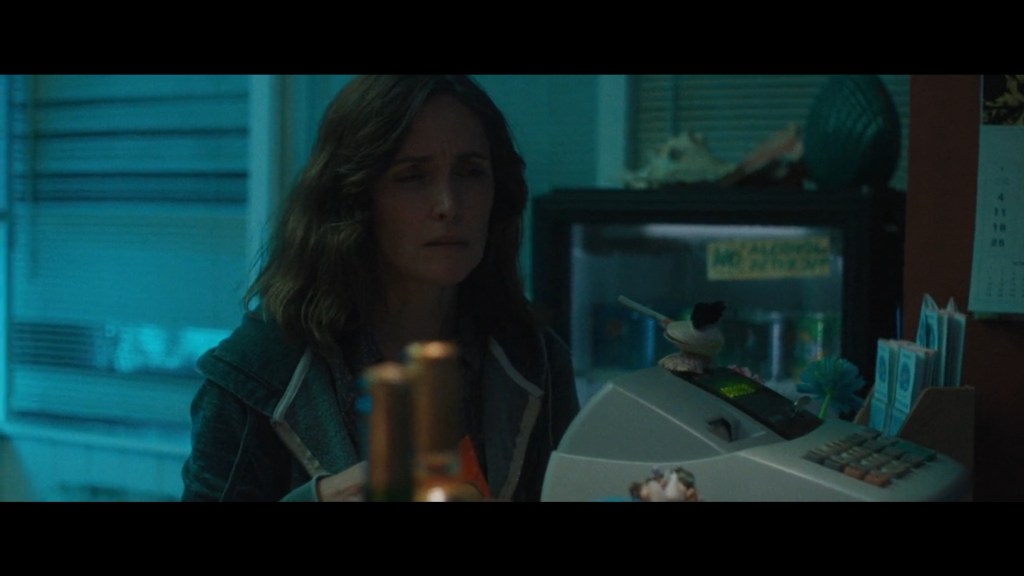 Close-up of Linda, who is obviously stoned, looking puzzled as she tries to purchase three bottles of wine