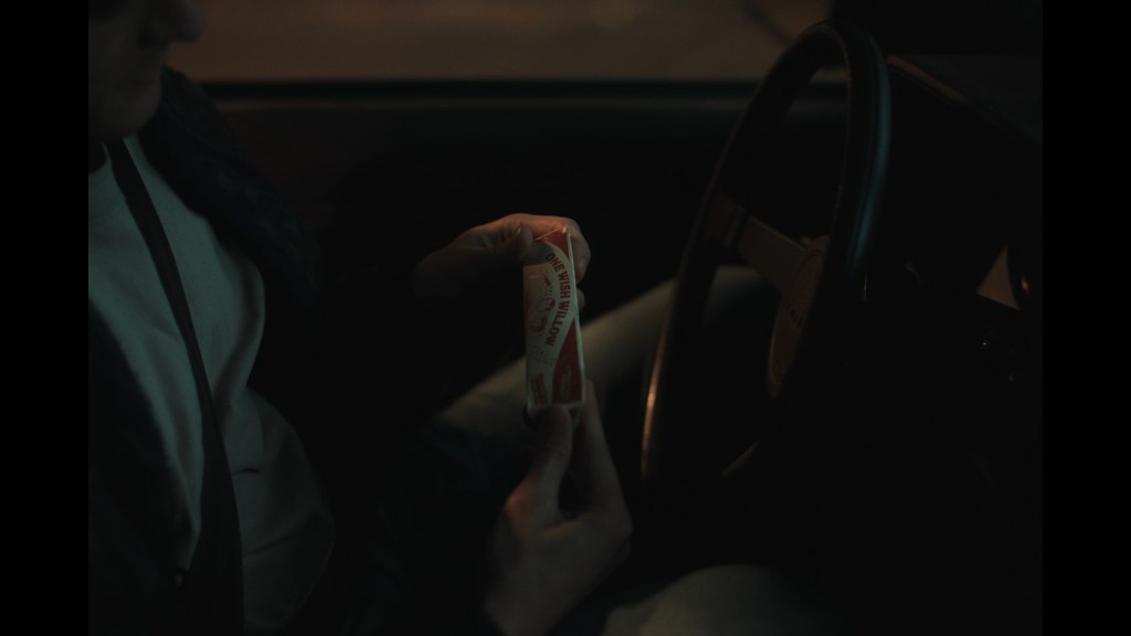 Close-up of Michael Johnston's Bear reading the words on a One Wish Willow box as he sits in his car at night
