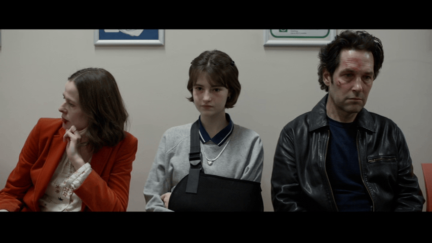 Medium long shot of Paul Rudd's Rick in a hospital recovery room with his wife (Marcella Plunkett) and daughter (Beth Fallon)