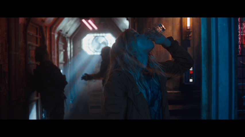 Blue-toned medium close-up of Kara downing a glass of alcohol in an extraterrestrial dive bar