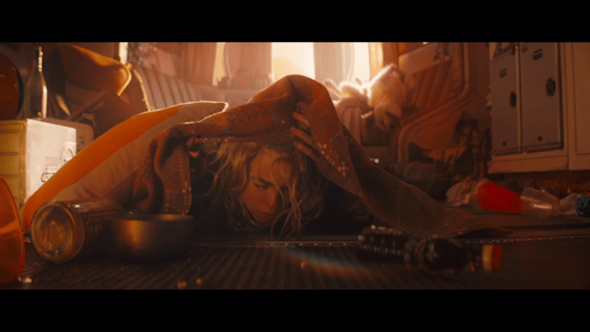Close-up of Kara waking up on the floor with another hangover from under the same blanket as the first image in this sequence
