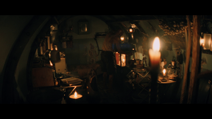 Fisheye lens long shot of Kelson's candlelit bunker